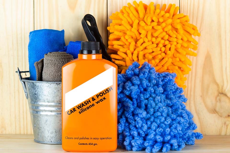 Car wash equipment or car cleaning product such as brush with mitts and microfiber tank and etc, on wooden table.